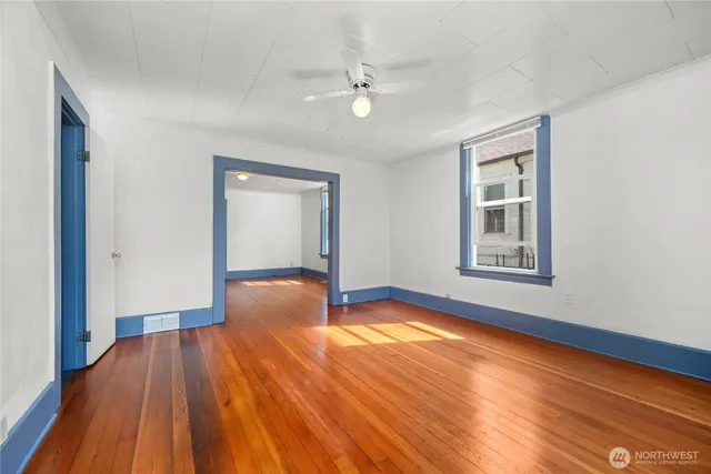 a view of an empty room with wooden floor and a window