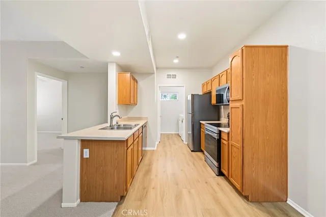 a kitchen with stainless steel appliances granite countertop a refrigerator a sink dishwasher and a stove with wooden floor