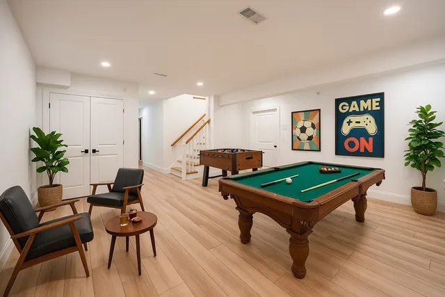 a room with furniture pool table and paintings on the wall