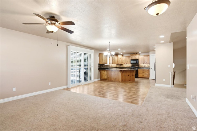 1089 West 2325th Street North Layton, UT 84041 - Photo 5 of 40 Open-concept living space featuring a ceiling fan, sliding glass doors with plantation shutters, wood-finish flooring, a kitchen with wood cabinetry, and recessed lighting