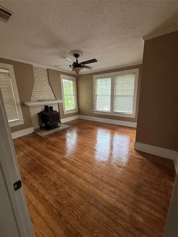 a view of an empty room with wooden floor fireplace and a window