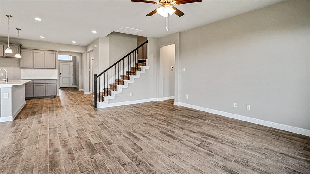 133 Hugo Court Rhome, TX 76078 - Photo 13 of 40 a view of staircase and kitchen with sink wooden floor and a chandelier