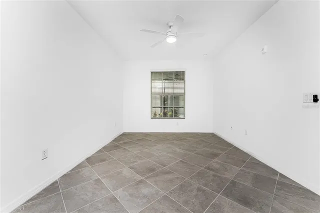 an empty room with windows and ceiling fan