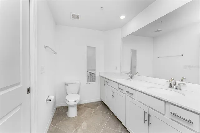 a spacious bathroom with a double vanity sink toilet and a mirror