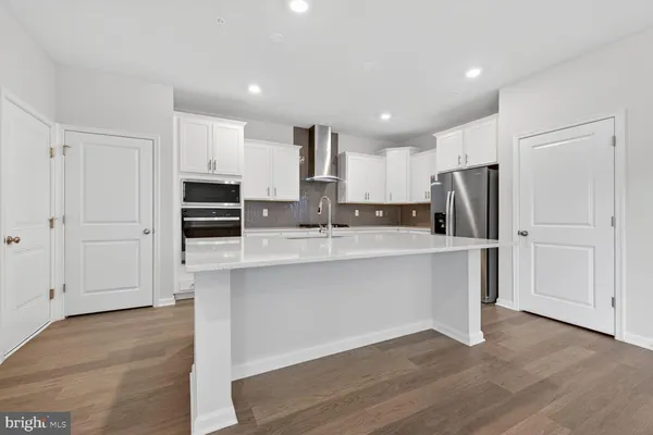a kitchen with stainless steel appliances white cabinets a sink a stove a microwave and wooden floors