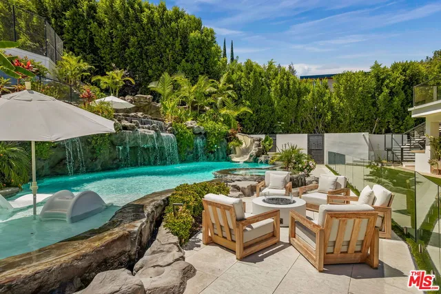 a view of a patio with couches table and chairs under an umbrella