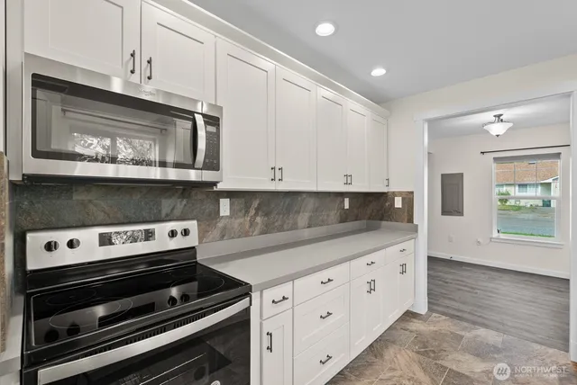 a kitchen with granite countertop white cabinets appliances and a counter space