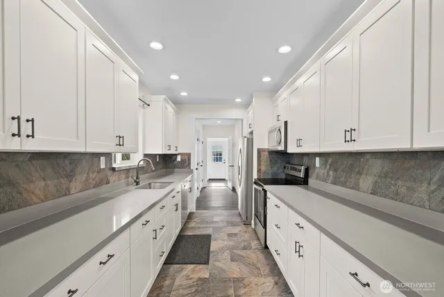 a large kitchen with stainless steel appliances granite countertop a sink and cabinets