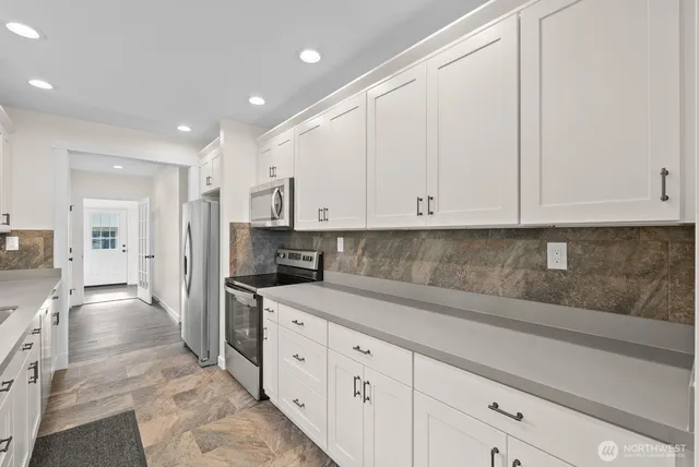 a kitchen with granite countertop white cabinets and stainless steel appliances