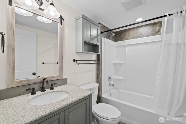 a bathroom with a granite countertop sink mirror toilet and bathtub