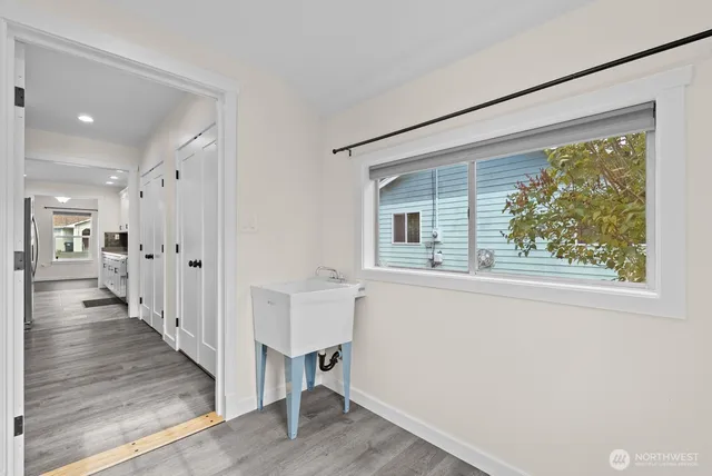 a view of a hallway with wooden floor and a bathroom
