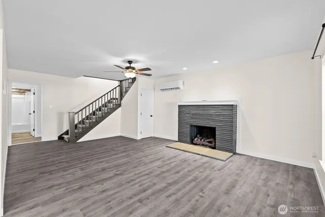 a view of an empty room with wooden floor fireplace and a window