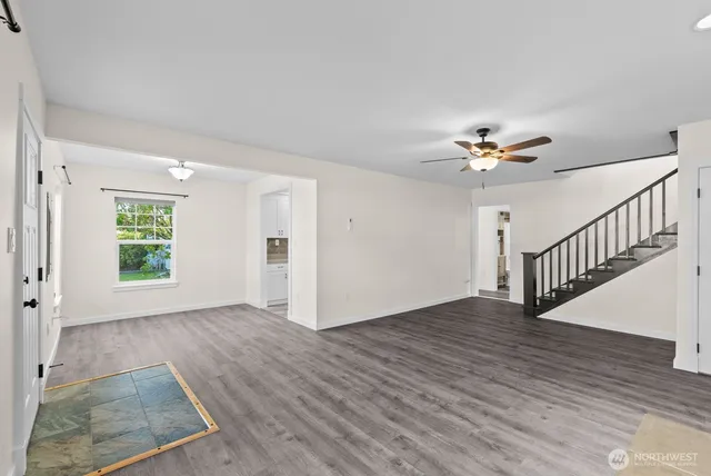 a view of an empty room with a window and wooden floor