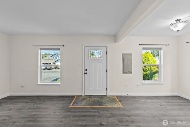a view of an empty room with window and wooden floor