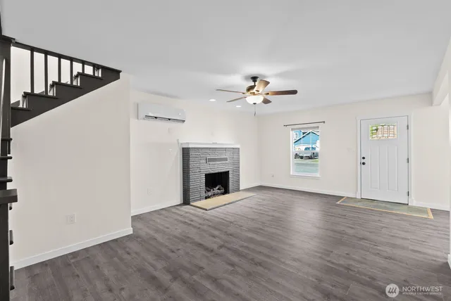 a view of an empty room with wooden floor and fireplace