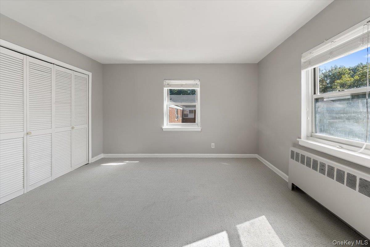 470 Tuckahoe Road, Unit 4B Yonkers, NY 10710 - Photo 16 of 17 Unfurnished bedroom featuring radiator, multiple windows, light carpet, and a closet