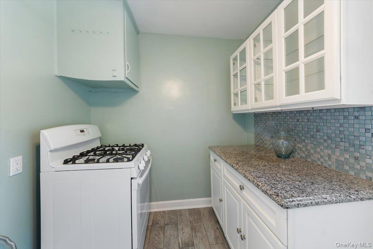470 Tuckahoe Road, Unit 4B Yonkers, NY 10710 - Photo 9 of 17 Kitchen featuring gas range gas stove, glass insert cabinets, white cabinets, light wood-style flooring, and light stone countertops