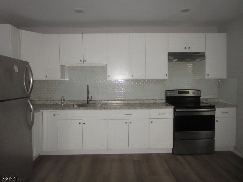 437 7th Avenue, Unit 4 Newark, NJ 07107 - Photo 2 of 7 a kitchen with granite countertop white cabinets and black appliances
