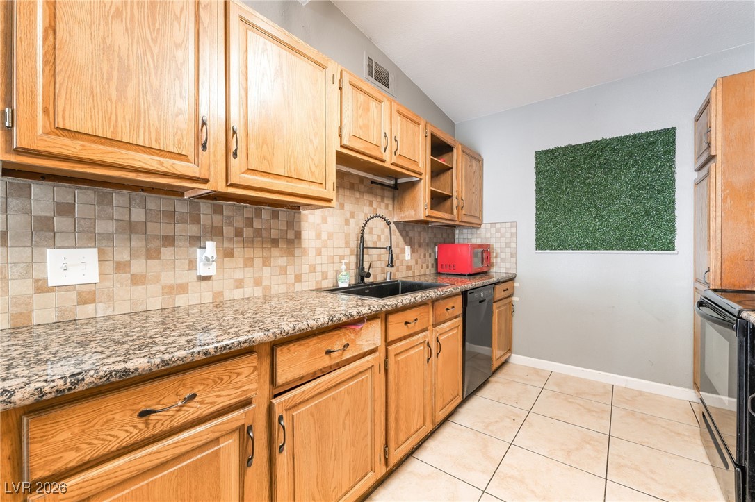 716 North 18th Street Las Vegas, NV 89101 - Photo 17 of 39 Kitchen featuring open shelves, light stone counters, light tile patterned floors, black appliances, and backsplash