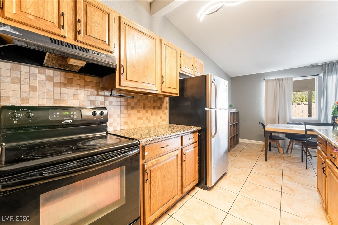716 North 18th Street Las Vegas, NV 89101 - Photo 19 of 39 Kitchen with black / electric stove, under cabinet range hood, freestanding refrigerator, decorative backsplash, and light stone countertops
