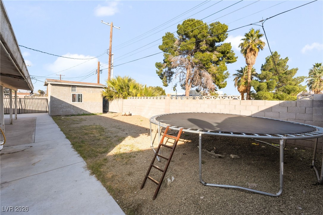 716 North 18th Street Las Vegas, NV 89101 - Photo 38 of 39 Fenced backyard with a trampoline, an outbuilding, and a patio