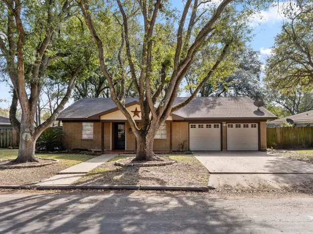 a front view of a house with a yard and large trees