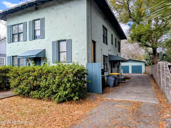 a view of a house with a barbeque and potted plants