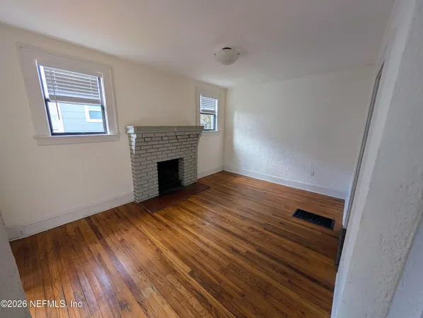 a view of empty room with wooden floor and fireplace