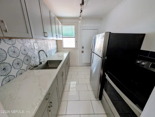 a kitchen with granite countertop a refrigerator and a sink