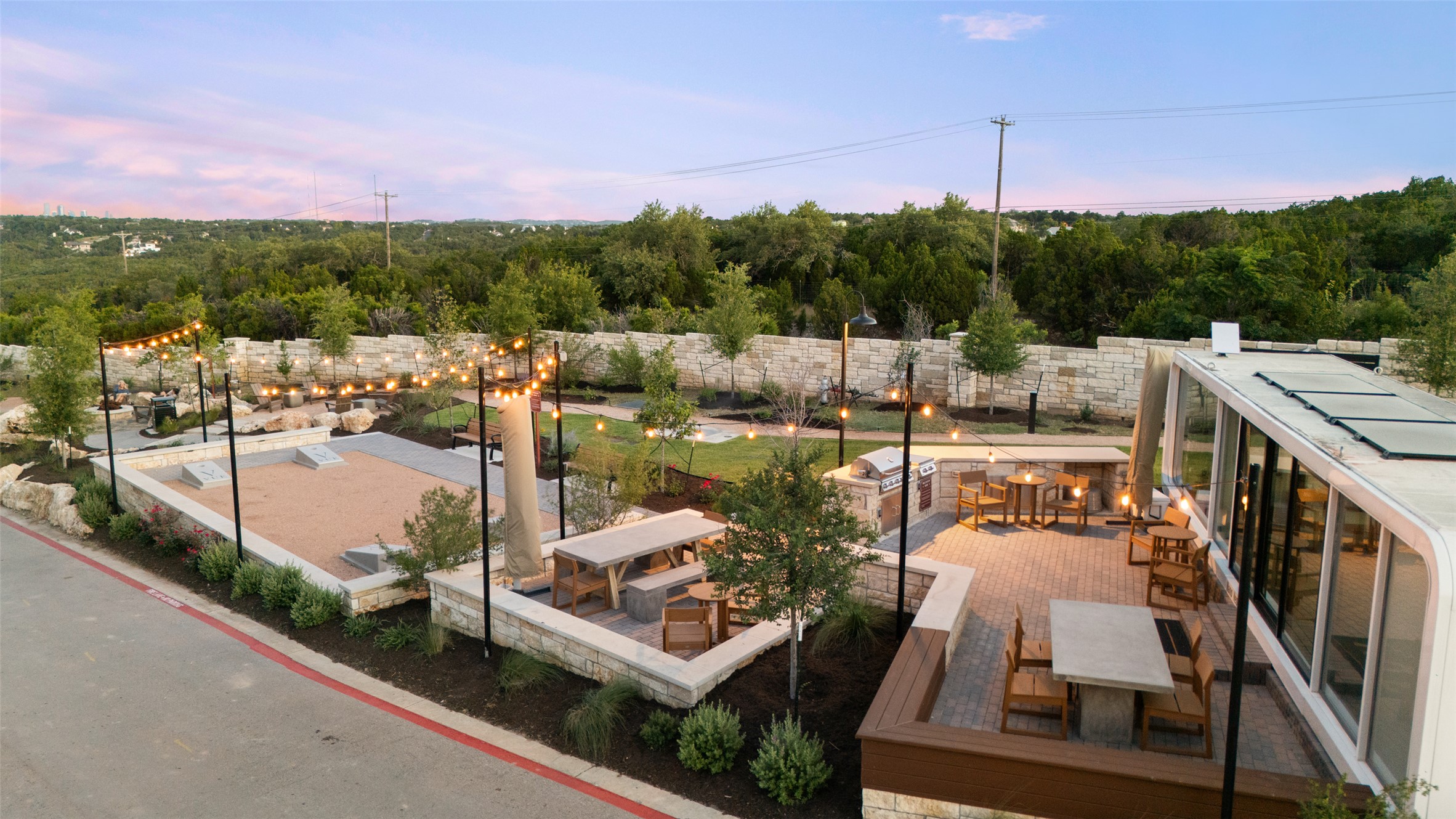 9803 Ribelin Ranch Court, Unit 9 Austin, TX 78750 - Photo 13 of 15 A spacious stone patio overlooks rolling green hills under a twilight sky.