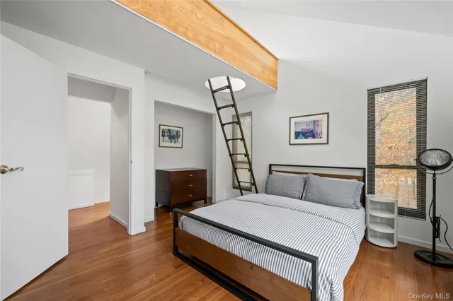 a bedroom with a bed a chair and a potted plant on the dresser