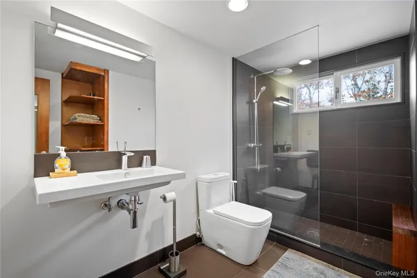 a bathroom with a sink a mirror a toilet and shower