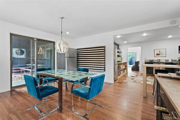 a open kitchen with stainless steel appliances granite countertop a stove top oven a dining table and chairs with wooden floor