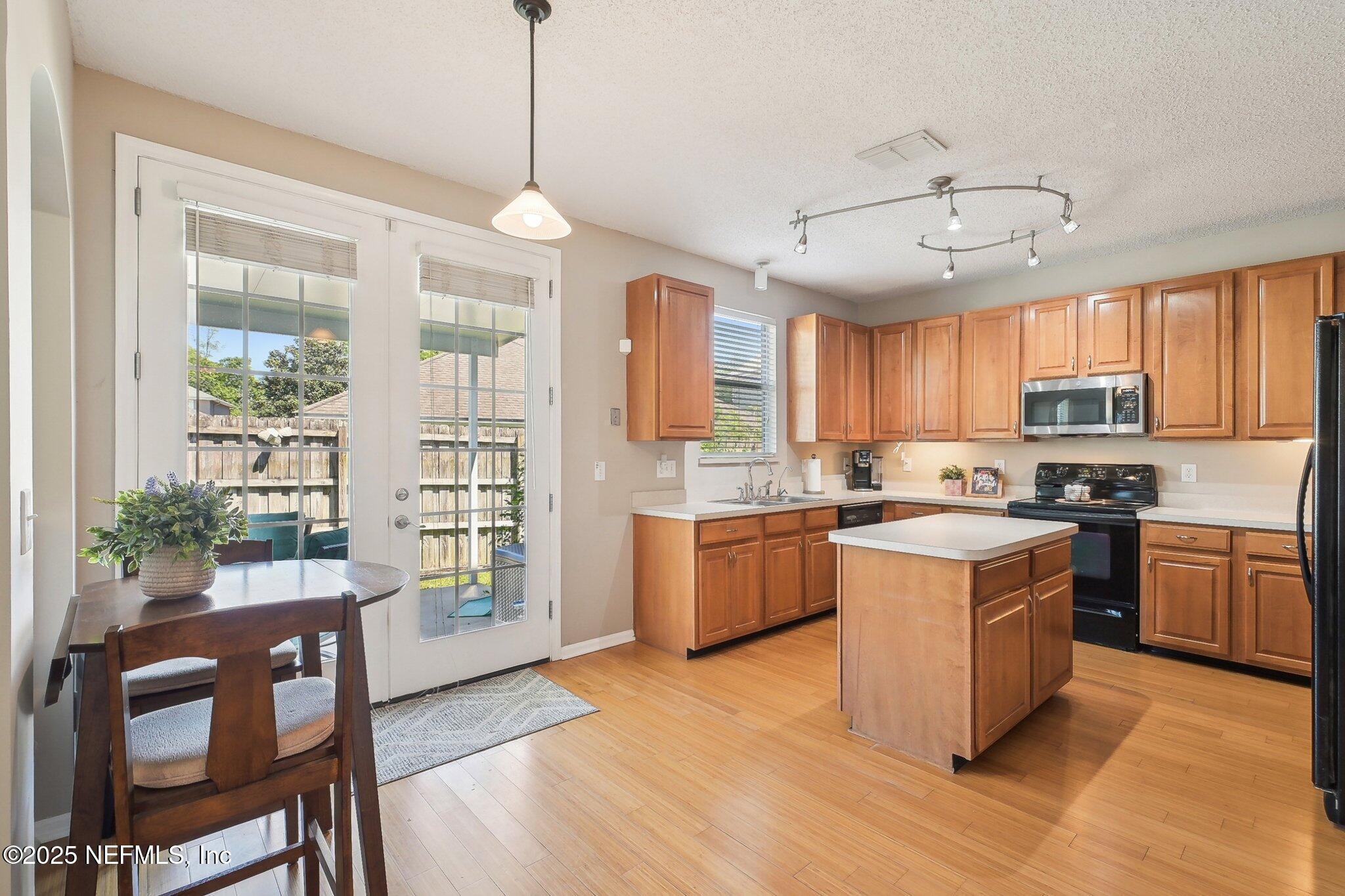 12529 Cliffrose Trail Jacksonville, FL 32225 - Photo 9 of 23 a kitchen with stainless steel appliances granite countertop a refrigerator a stove top oven a sink dishwasher and a dining table with wooden floor