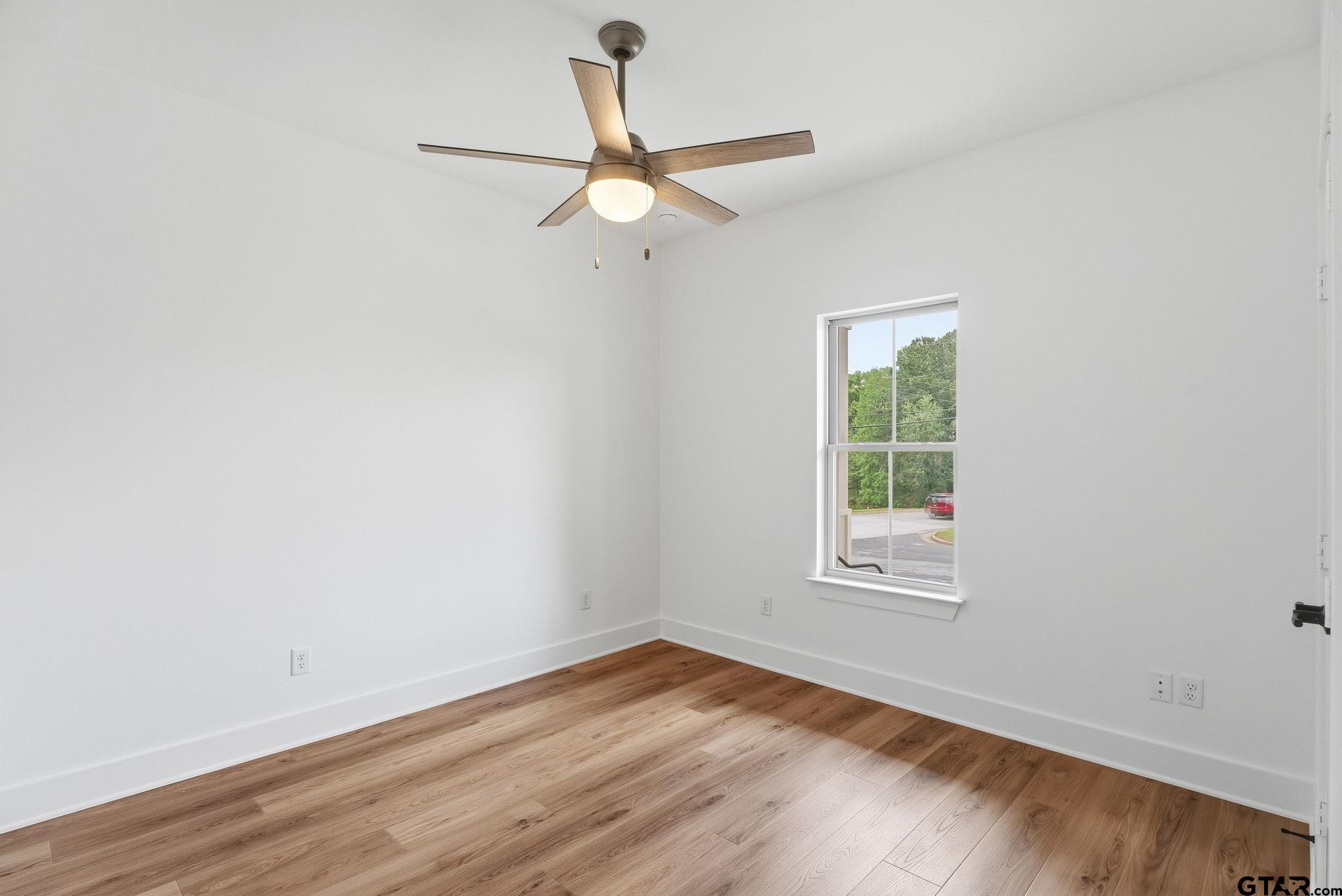 2968 Calloway Road Tyler, TX 75701 - Photo 13 of 24 an empty room with wooden floor ceiling fan and windows