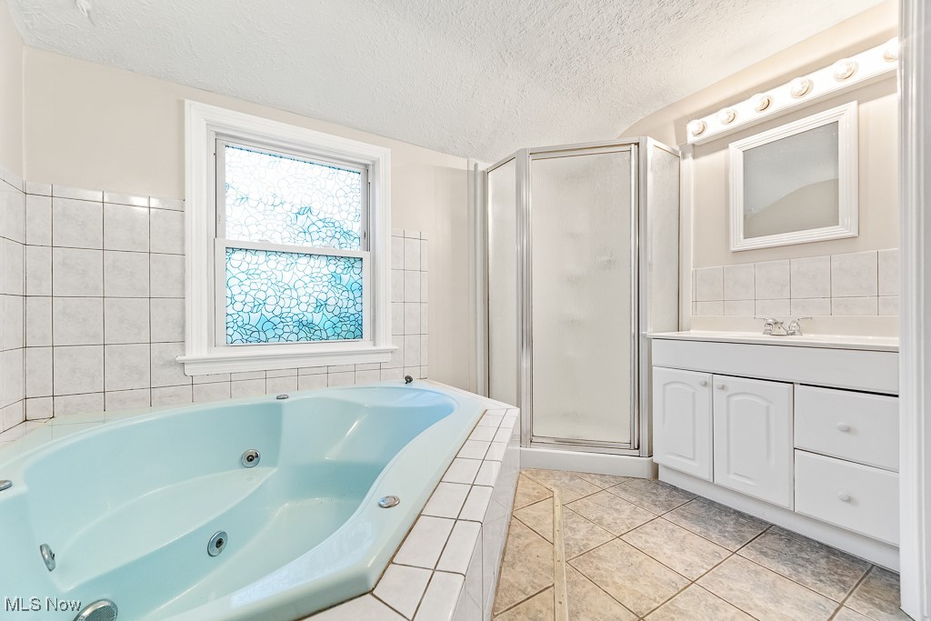 9049 Prospect Road Strongsville, OH 44149 - Photo 26 of 50 Bathroom with vanity, a textured ceiling, tile patterned floors, and separate shower and tub