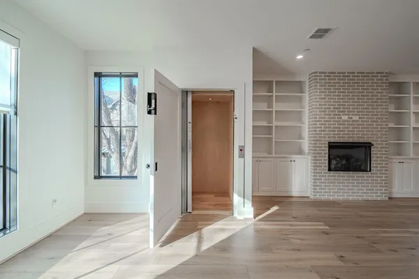 a view of an empty room with wooden floor and a fireplace