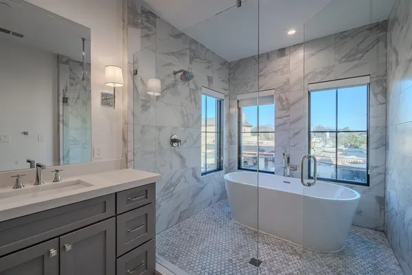 a spacious bathroom with a tub sink shower and mirror