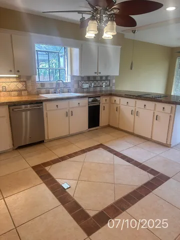 a large parking space with stainless steel appliances granite countertop a sink and cabinets