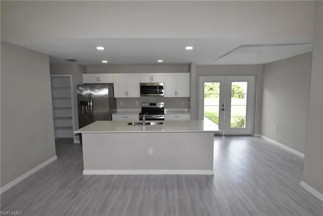 a living room with stainless steel appliances wooden floors and large window