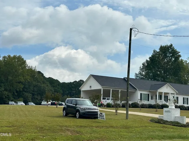 a front view of a house with a garden and trees