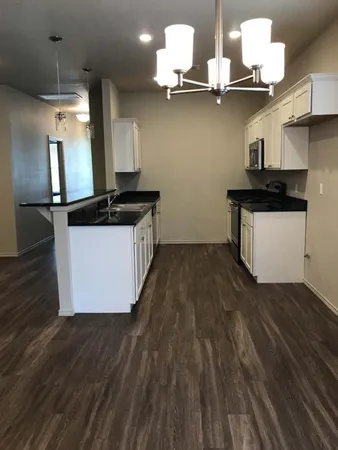 a kitchen with stainless steel appliances granite countertop a sink a stove and a wooden floors