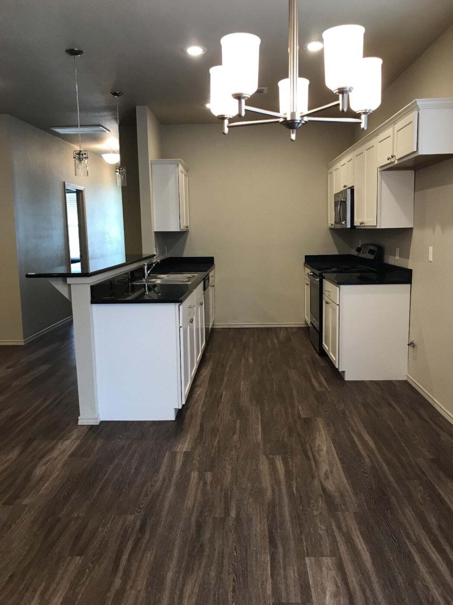 2101 10th Street Lubbock, TX 79401 - Photo 5 of 8 a kitchen with stainless steel appliances granite countertop a sink a stove and a wooden floors