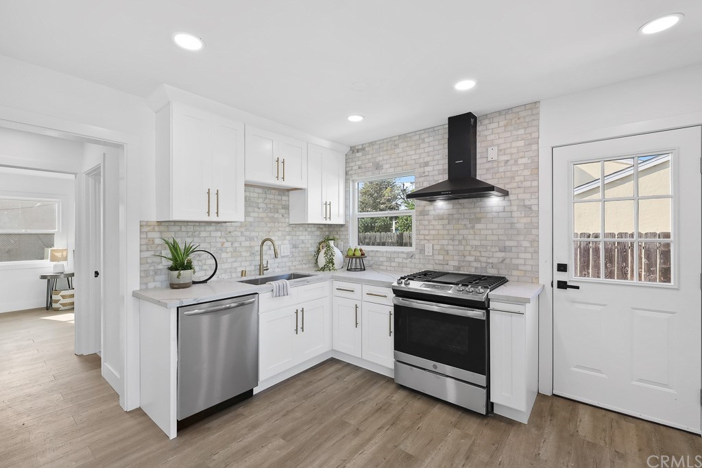 a kitchen with stainless steel appliances granite countertop white cabinets a stove a sink and a refrigerator