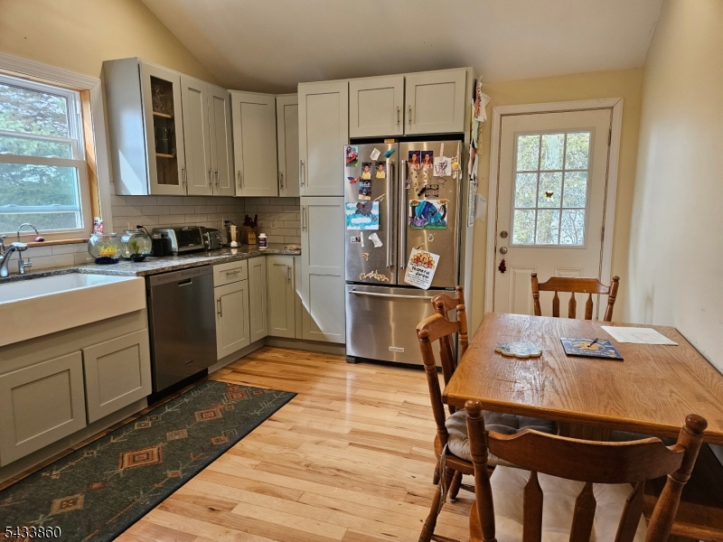 106 Lake Wallkill Road Vernon, NJ 07461 - Photo 10 of 24 a kitchen with granite countertop a refrigerator a stove a sink dishwasher and white cabinets with wooden floor