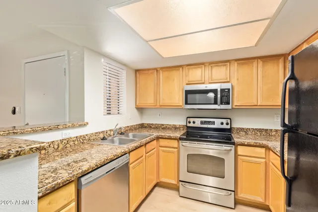 a kitchen with granite countertop a sink stainless steel appliances and counter space
