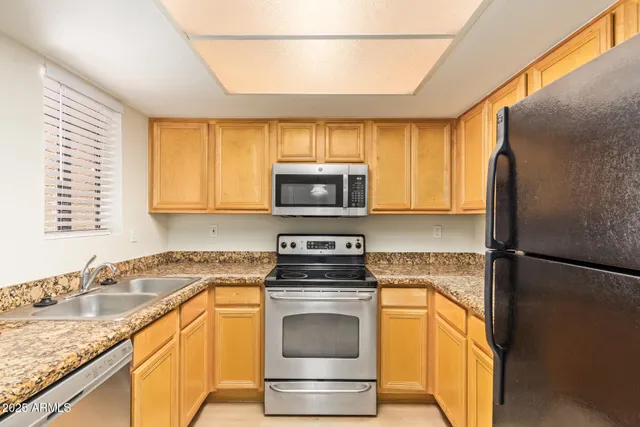 a kitchen with granite countertop a sink stove and refrigerator
