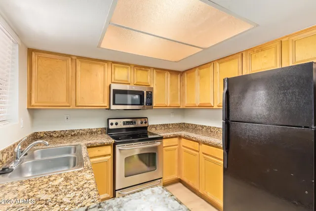 a kitchen with stainless steel appliances granite countertop a refrigerator sink stove microwave and cabinets