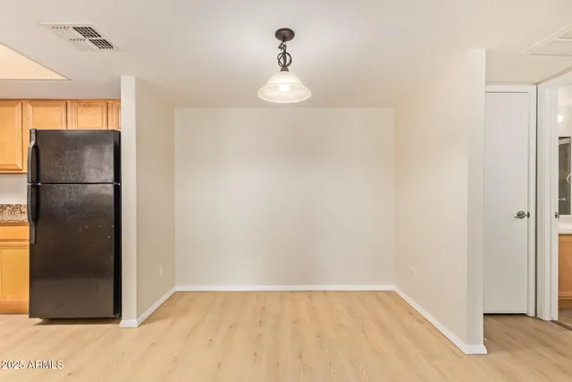 a view of a refrigerator in kitchen and an empty room