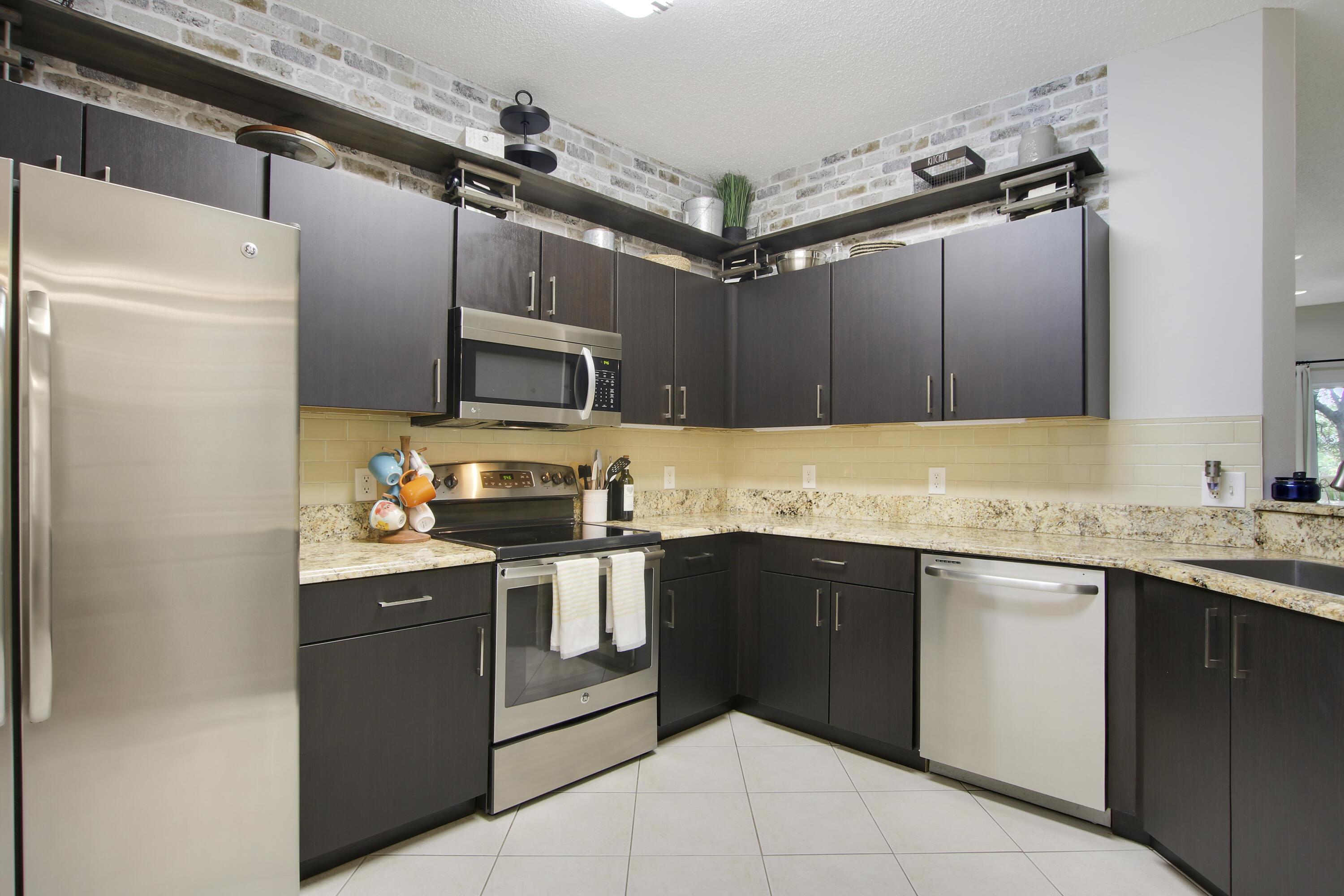115 Lighthouse Circle, Unit D Tequesta, FL 33469 - Photo 7 of 28 a kitchen with granite countertop a sink stainless steel appliances and cabinets